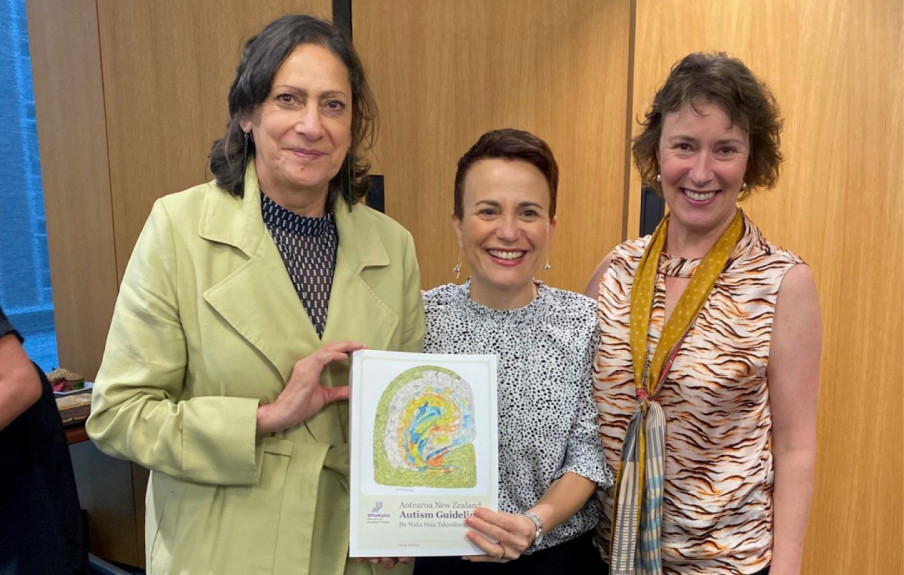3 smiling women Minister Poto Williams who is wearing a light green jacket, Paula Tesoriero CE of Whaikaha in a black and white top and Marita Broadstock, Living Guideline Manager in tiger print. Paula is holding a copy of the guidelines.