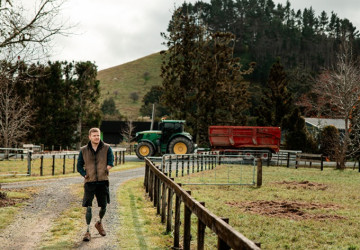Man walking on a farm track with a tractor and paddocks nearby.