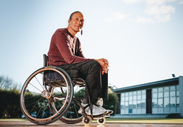 Māori man in a wheelchair outside a building.